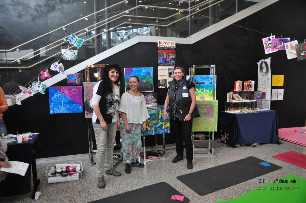 Carolina, Kari Anne og prosjektansvarlige, Irene Sandved, viser stolt frem malerier og keramikk laget av flyktninger under kunstuttrykks workshop.